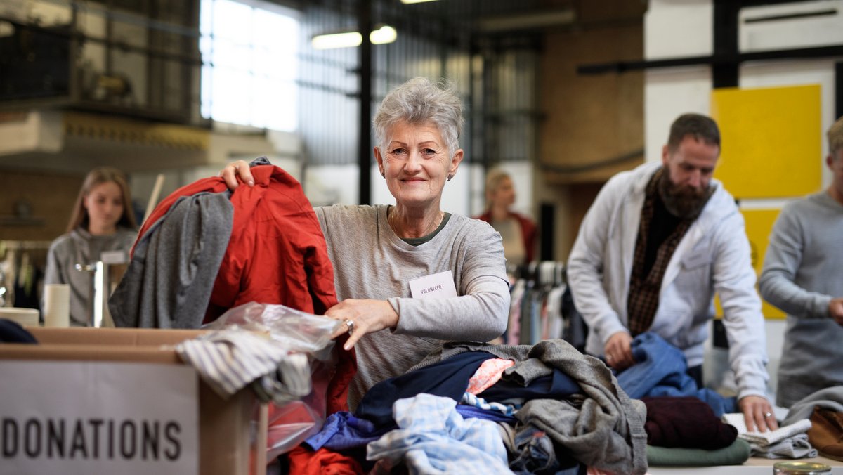 I AM SAVED BY GRACE NOT BY WORKS::VOLUNTEERS SORTING OUT DONATED CLOTHES © Pojoslaw | Dreamstime.com