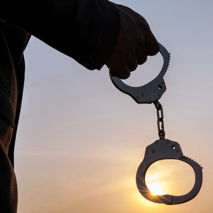 JESUS DELIVERED US FROM BONDAGE TO THE LAW::MAN HOLDING HANDCUFFS AFTER RELEASE © twinsterphoto | iStockPhoto.com