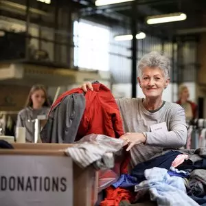 I AM SAVED BY GRACE NOT BY WORKS::VOLUNTEERS SORTING OUT DONATED CLOTHES © Pojoslaw | Dreamstime.com