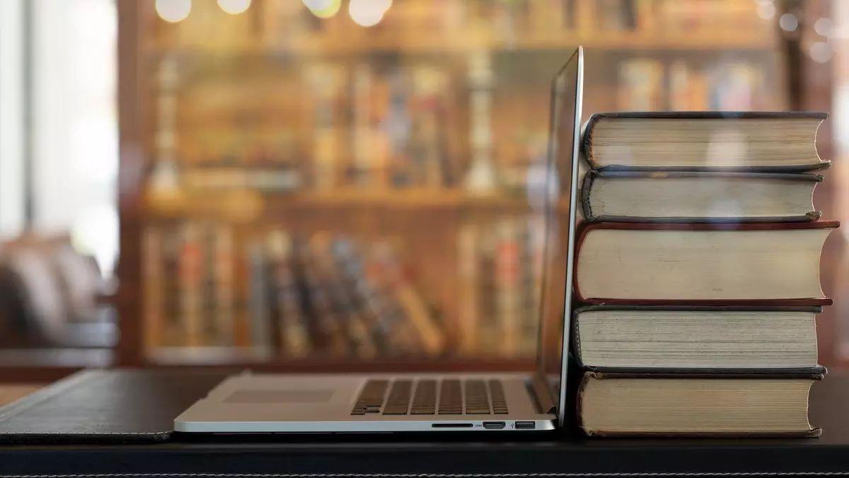 BOOK STACK AND LAPTOP ON DESK IN LIBRARY © utah778 | iStockPhoto.com
