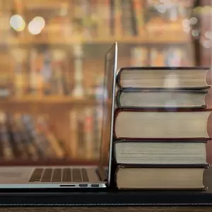 BOOK STACK AND LAPTOP ON DESK IN LIBRARY © utah778 | iStockPhoto.com